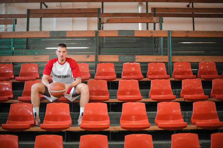 A tall basketball player looks directly into the camera.