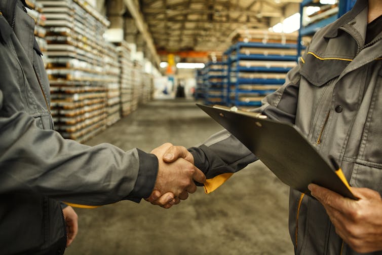 Close up of two workers shaking hands in a warehouse