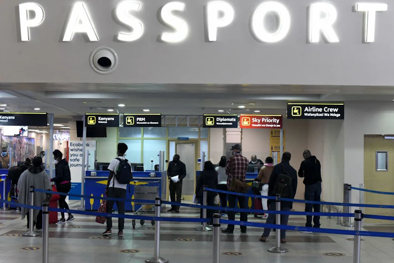 Interior of building with people standing in queues and a large sign saying "passport"