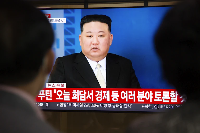People watch a TV screen with North Korean leader, Kim Jong-un, on it.