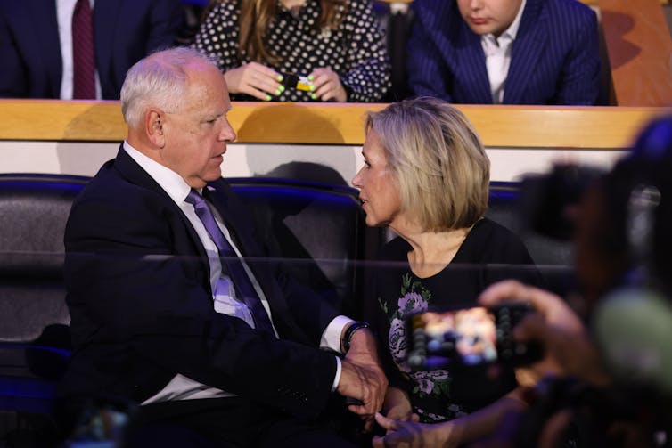 Democratic Party vice-presidential nominee Tim Walz sits holding hands with his wife Gwen.
