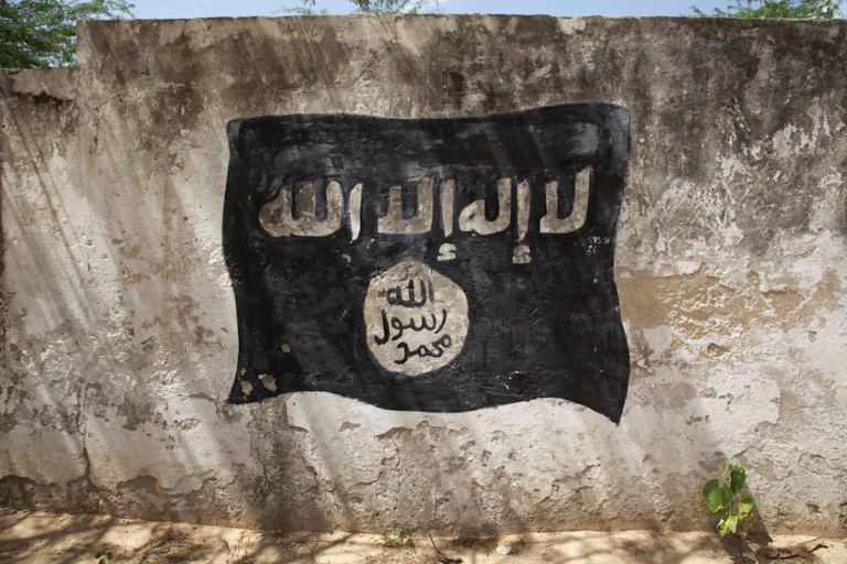 A black flag with white Arabic lettering painted on a wall