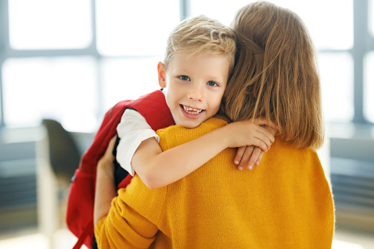 Boy in school uniform hugging mother