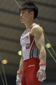 gymnast with chalky hands and eyes closed standing still