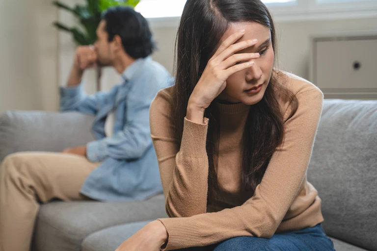 Two people sat on a sofa after an argument.