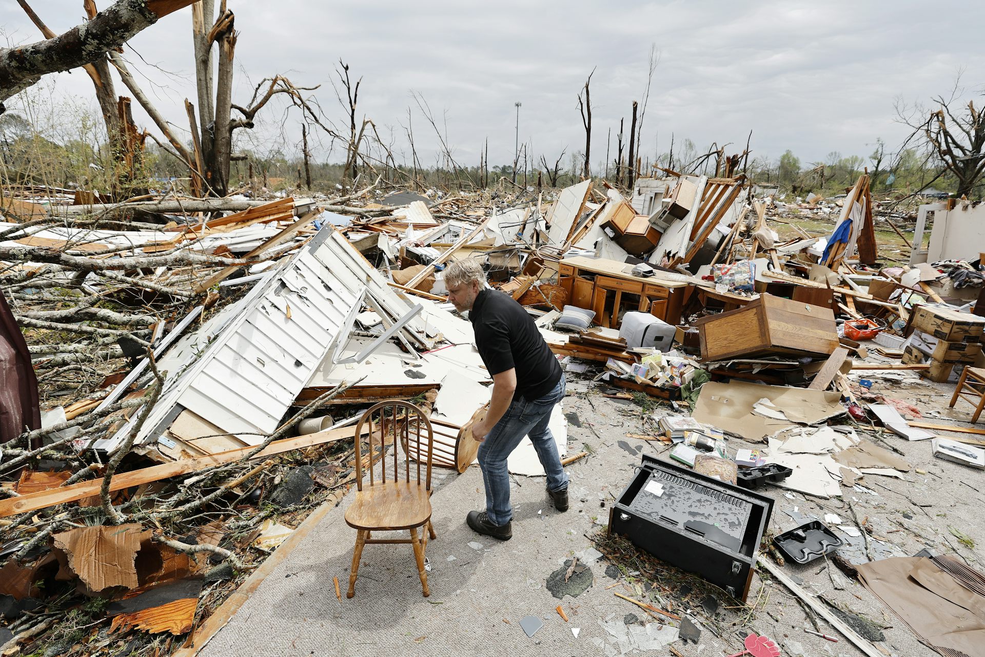A man shifting debris amid a scene of total devastation.