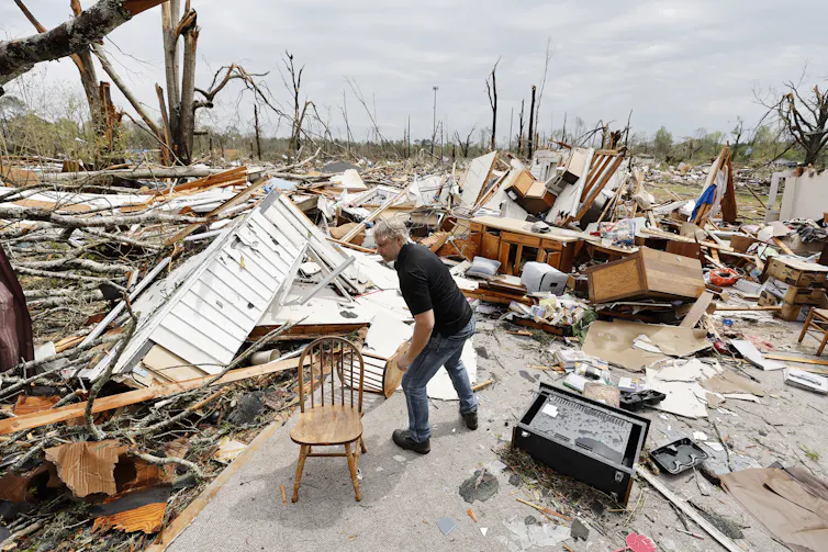A man shifting debris amid a scene of total devastation.