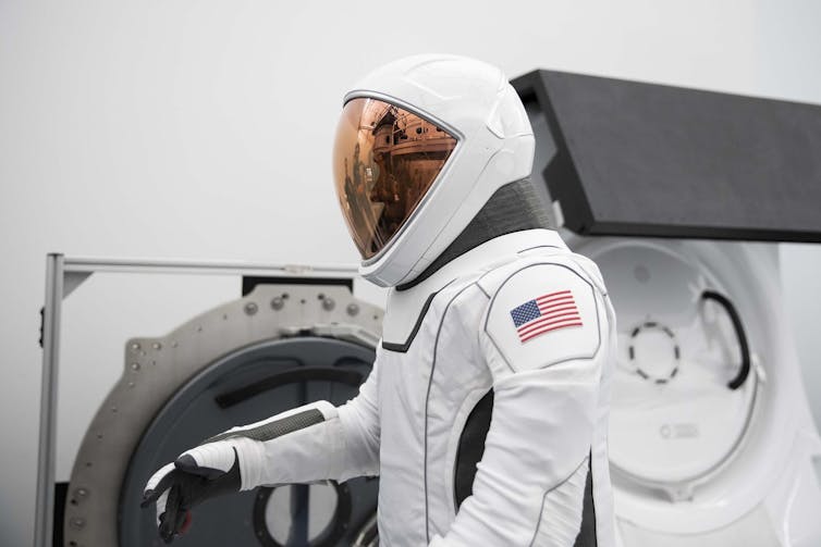 A person wearing a white spacesuit with a helmet that fully covers their face.