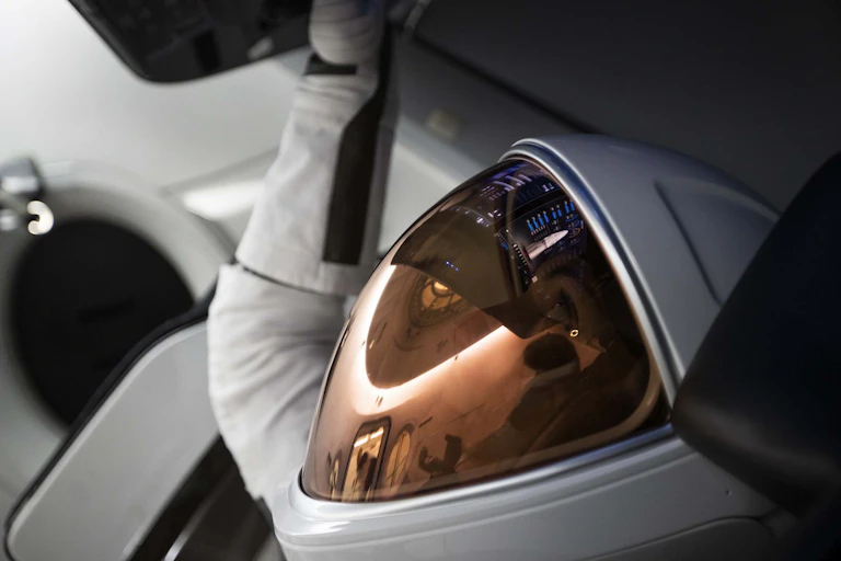 A close-up of a crew member's EVA helmet as they sit in a capsule.