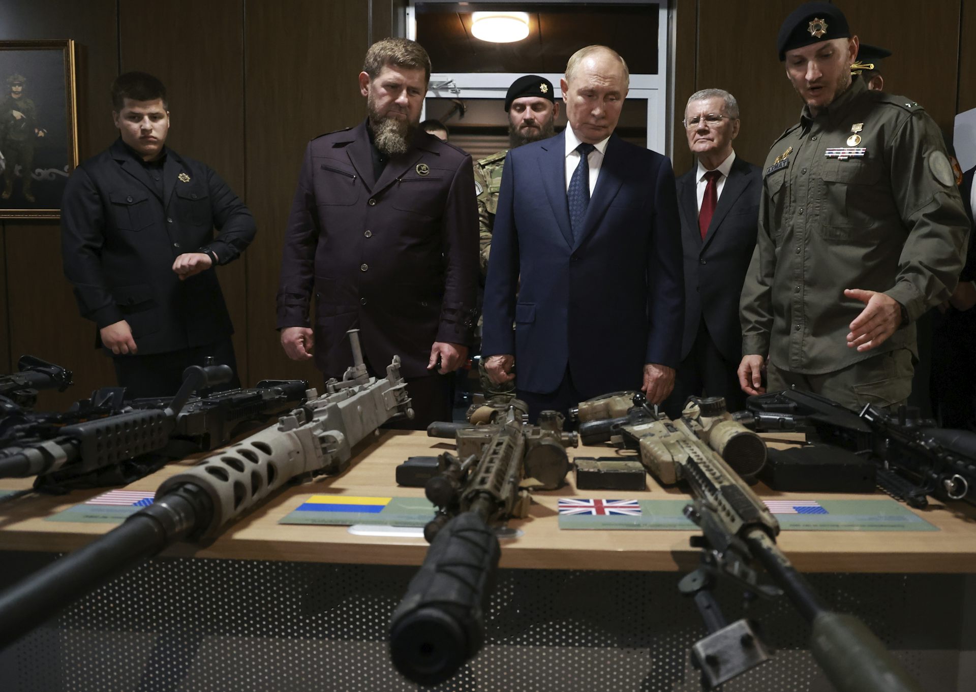 Vladimir Poutine et Ramzan Kadyrov debout devant une table où l’on aperçoit des armes