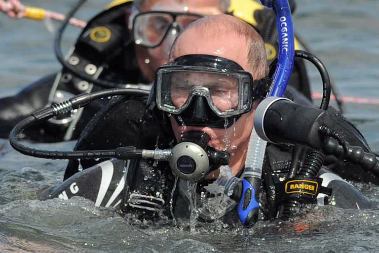 A man in diving equipment is seen exiting the water.
