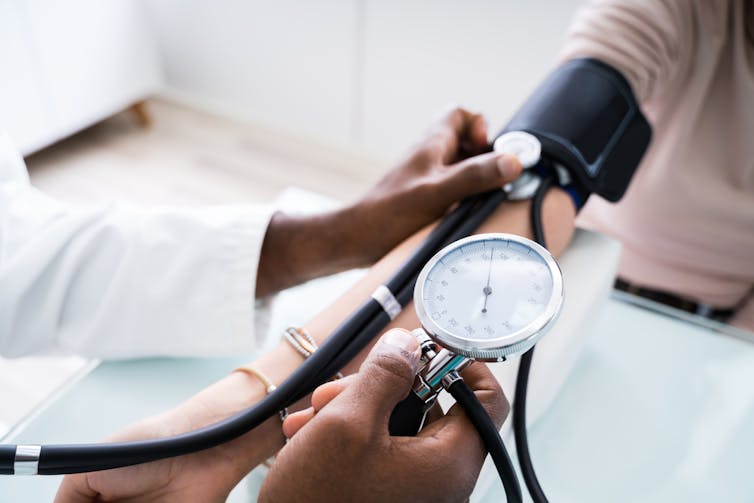 Doctor wearing white coat checking patient's blood pressure