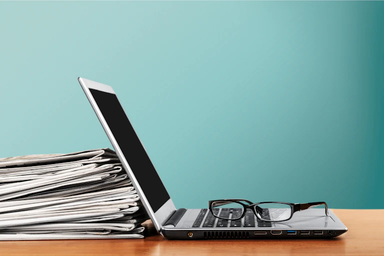 newspapers leaning against an open laptop