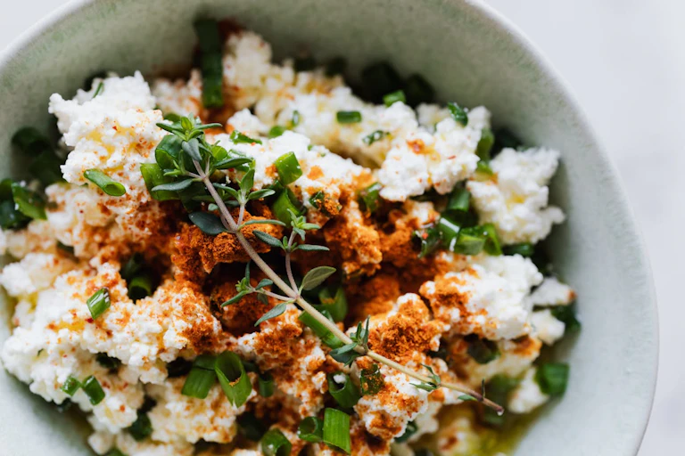 Bowl of cottage cheese, spring onion, herbs and spices