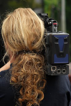 Reporter holding camera, seen from behind