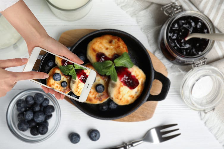 Woman taking picture of pancakes with smartphone