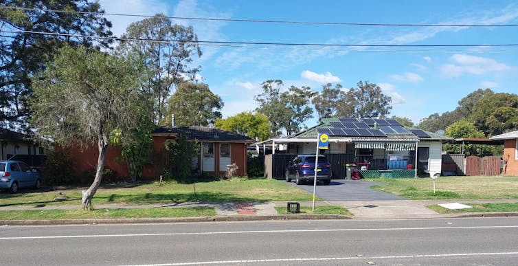 A milk crate has been placed next to a bus stop with no shelter or seating