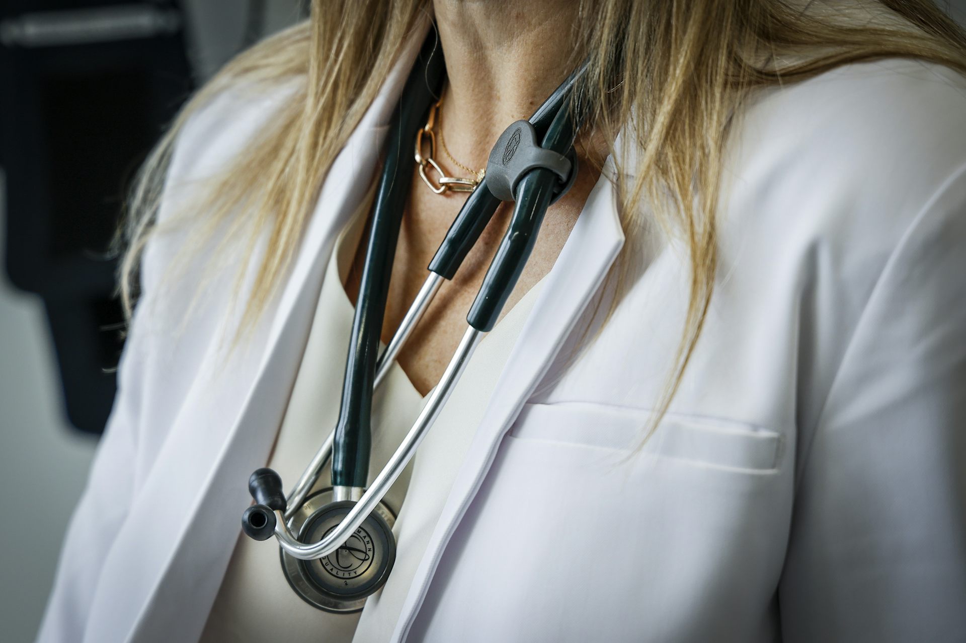 A doctor is photographed from the neck down with blonde hair, a lab coat and a stethoscope.