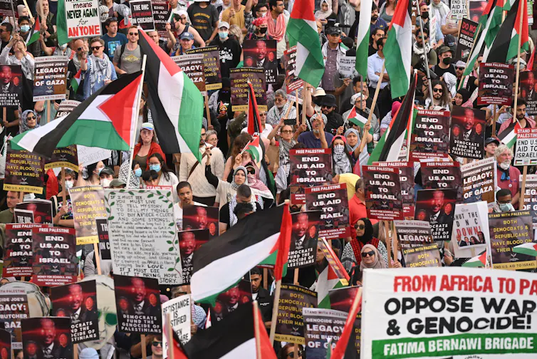 Pro-Palestinian protesters march carrying banners.