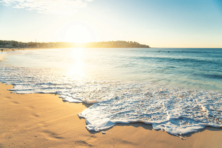 On the shore of a deserted beach: The blue sea, the brown sand and in the distance, the bright sun.