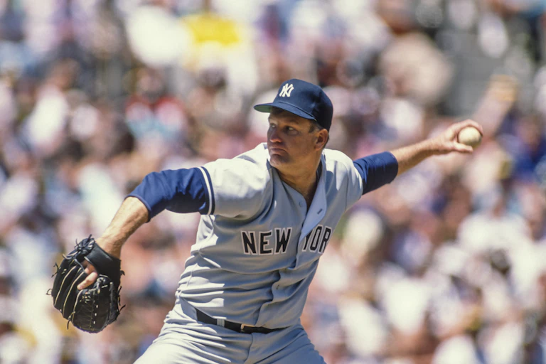 With thousands of baseball fans in the background, a left-handed pitcher on the mound prepares to fire the ball to home plate.
