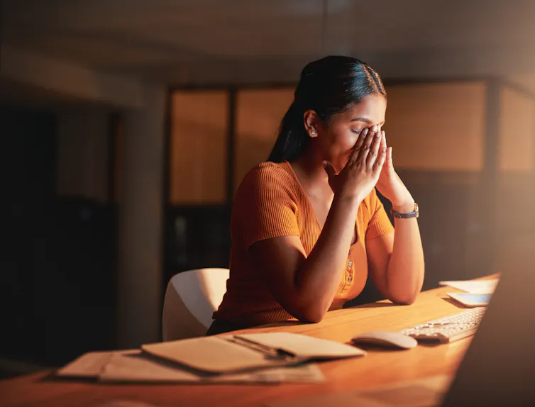 Young businesswoman sitting alone in the office at night and feeling stressed