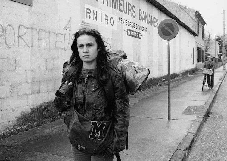 Una chica con una gran mochila camina por la acera.