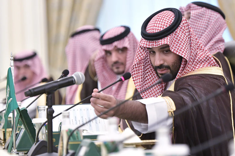 Mohammed bin Salman adjusting a microphone at a press conference.
