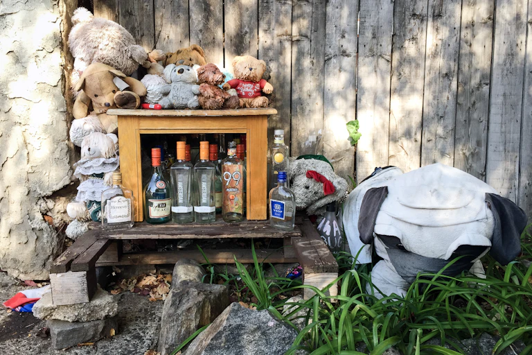 Makeshift memorial made from wooden pallet, table, empty liquor bottles and stuffed animals