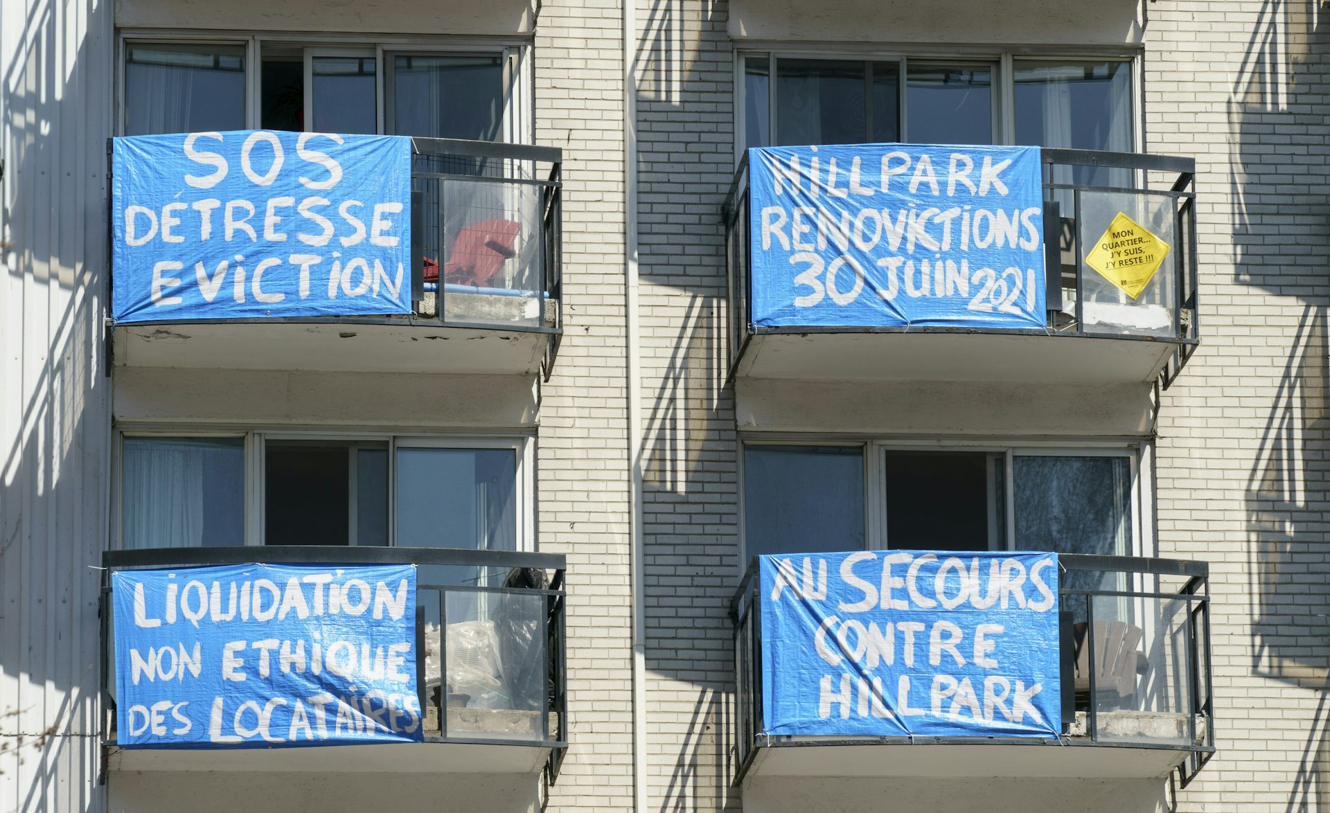 Blue banners with anti-renoviction slogans hang from the balconies of an apartment building