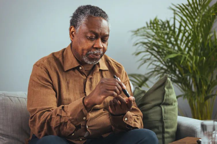 A senior man applying a device to his finger to measure blood sugar levels.
