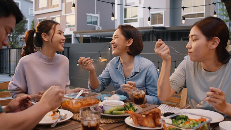 Friends eat dinner on a rooftop terrace