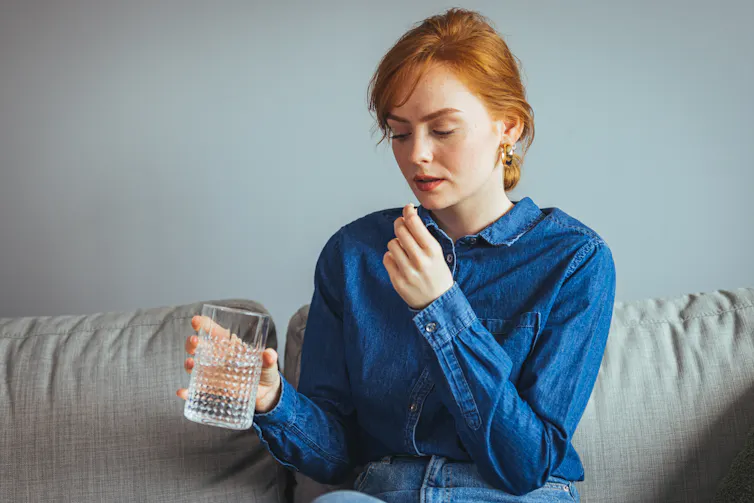A young woman taking a tablet.