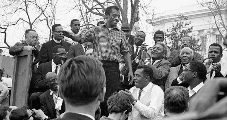 A man (James Baldwin) addressing a crowd of demonstrators in 1960s America.