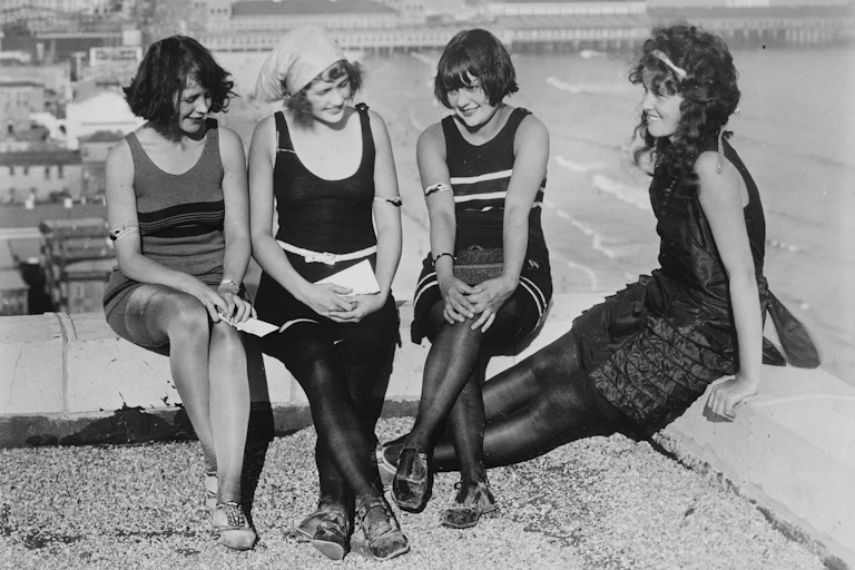 Black and white photo of four young women sitting on a roof in the 1920s.