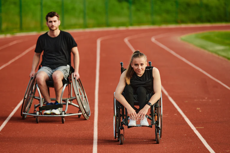 Un homme et une femme en fauteuil sur une piste d'athlétisme.