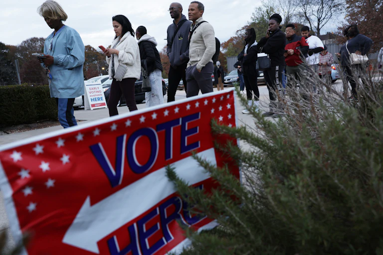 A line of voters of different races wait in line to cast their ballots.