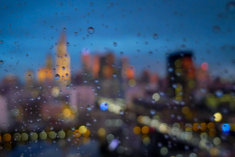 Looking out a rain-spattered window onto a city skyline.