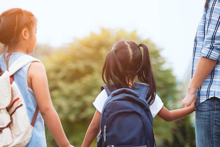Children hold hands with a parent.