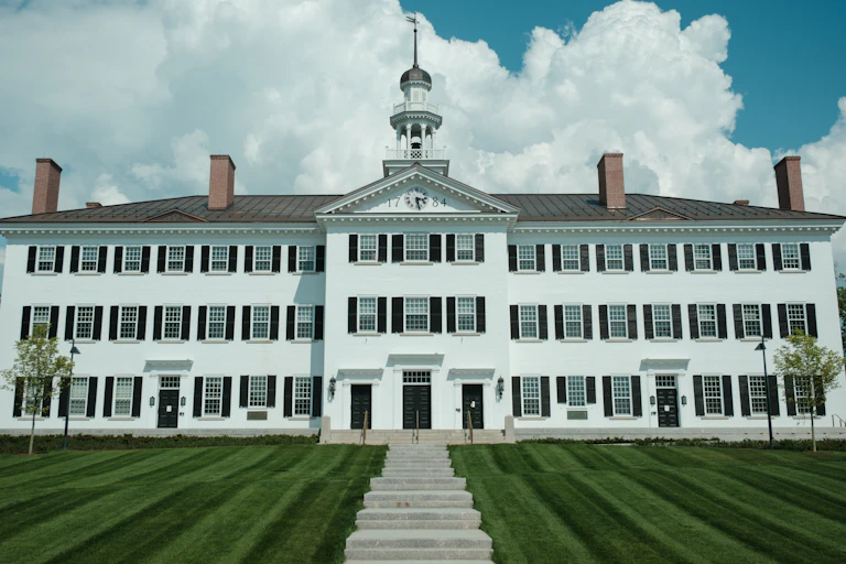 A staircase leading through a manicured lawn to a historic white university hall
