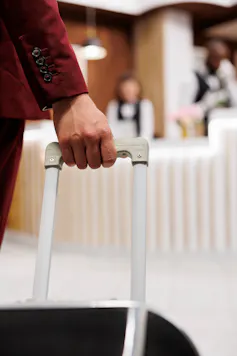 person holding baggage enters hotel reception front desk