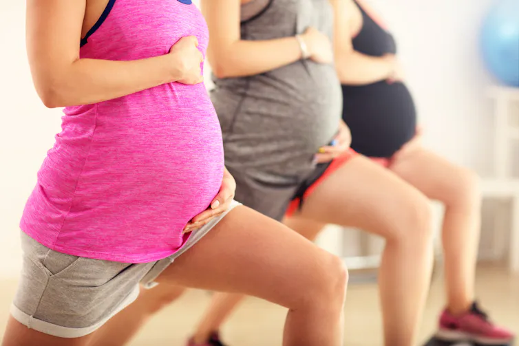 Three pregnant bellies during a stretching class.