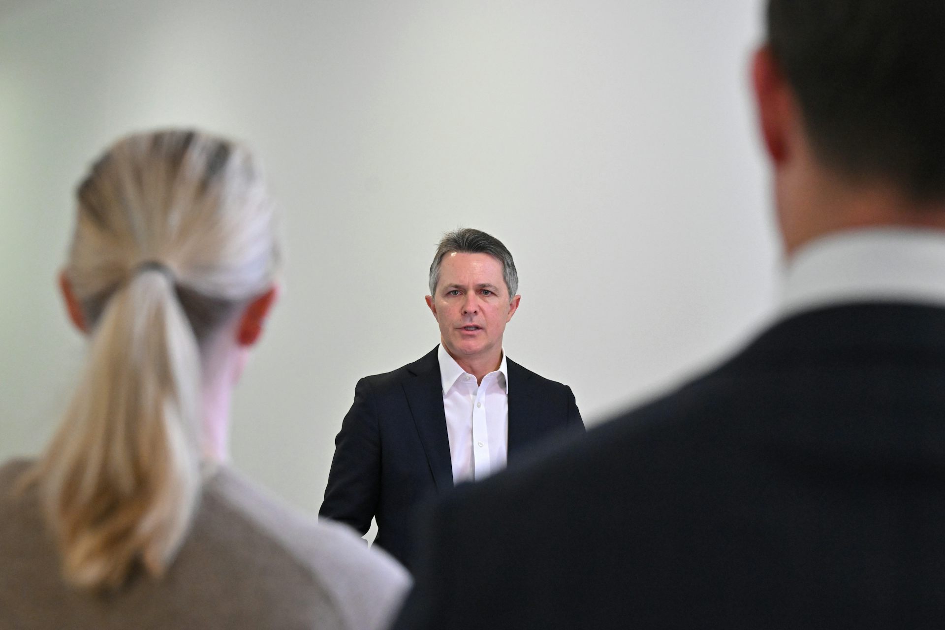 Education Minister Jason Clare speaks to two journalists.