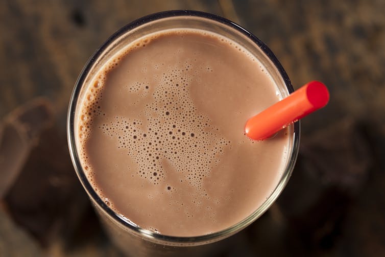 A birds-eye view of a glass of chocolate milk with a red straw.
