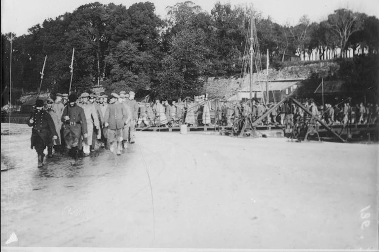 A black-and-white image of prison guards leading a line of prisoners back to jail.