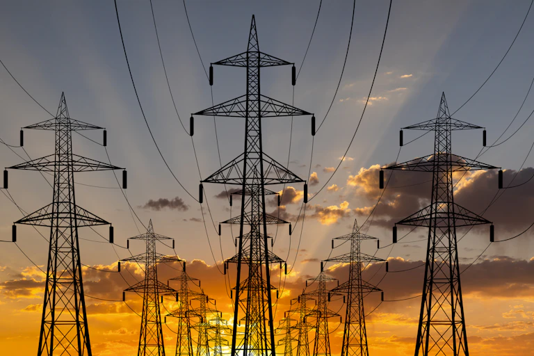 Electricity pylons silhouetted against the sky at sunset or sunrise