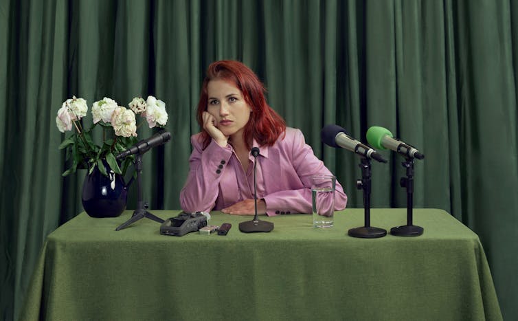 A woman sat in front of green microphones