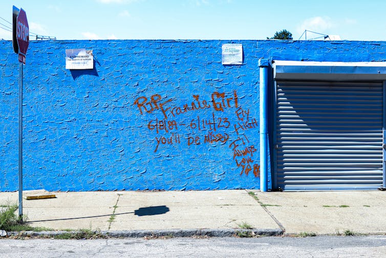 Red graffiti on a bright blue wall reads 'RIP Frannie Girl 6/8/89 - 6/14/23. Fly high. You'll be missed. I'll always love you.'