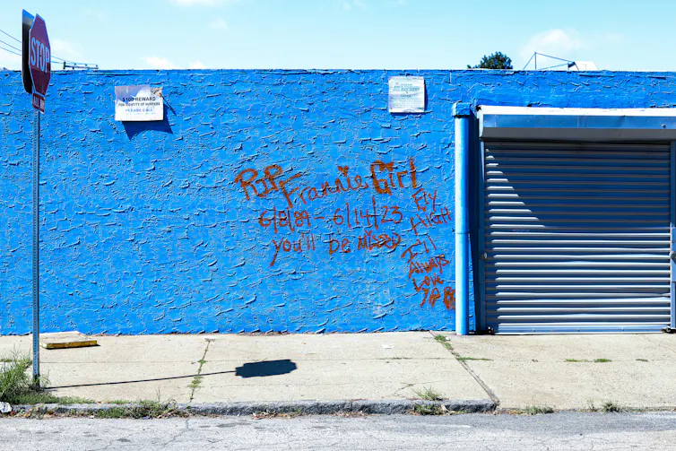 Red graffiti on a bright blue wall reads 'RIP Frannie Girl 6/8/89 - 6/14/23. Fly high. You'll be missed. I'll always love you.'