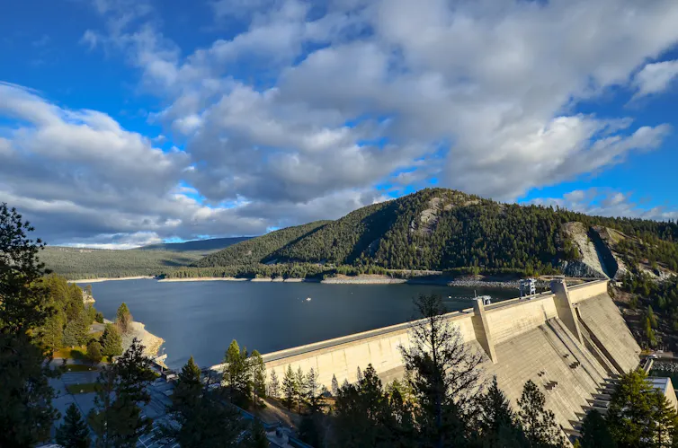 A dam holds back a lake under a blue sky.